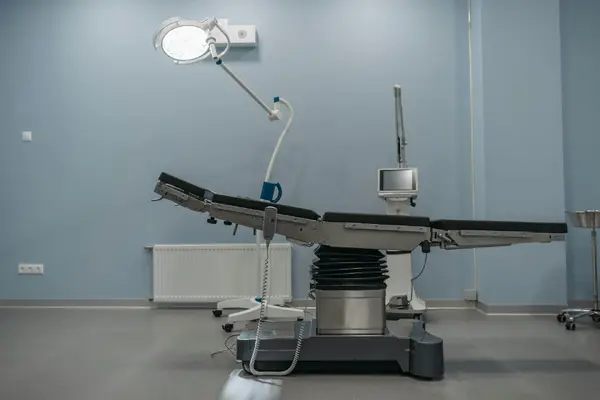 A clean, modern operating theatre with a surgical table and light