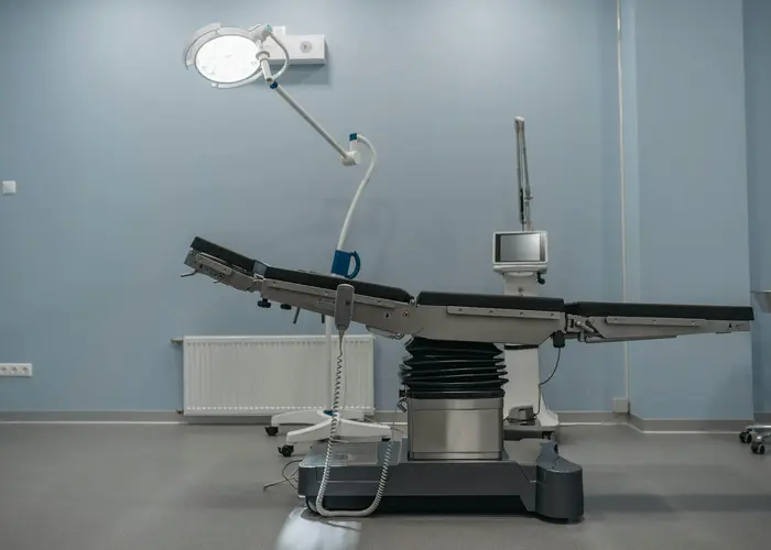 A clean, modern operating theatre with a surgical table and light