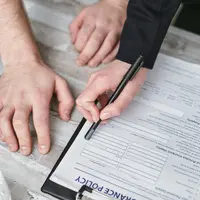 Two people reviewing an insurance policy document with a pen