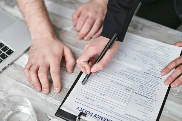 Two people reviewing an insurance policy document with a pen